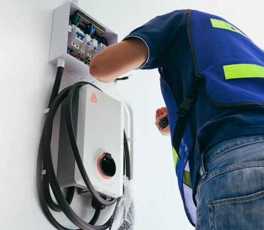 Photographie d'un technicien qualifié en tenue de travail professionnelle effectuant un diagnostic électrique ou une inspection technique dans un environnement résidentiel ou professionnel (intérieur moderne, tableau électrique, ou intervention sur installation), démontrant l'expertise et l'engagement professionnel, avec une expression concentrée et consciencieuse illustrant la fiabilité et le service client.