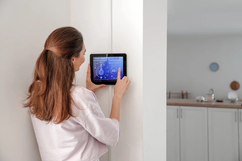 Intérieur moderne avec écran tactile mural intelligent affichant plan de maison avec points de contrôle lumineux