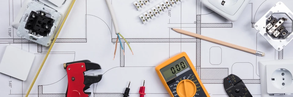 Un électricien travaille sur un tableau électrique à l'intérieur d'un bâtiment