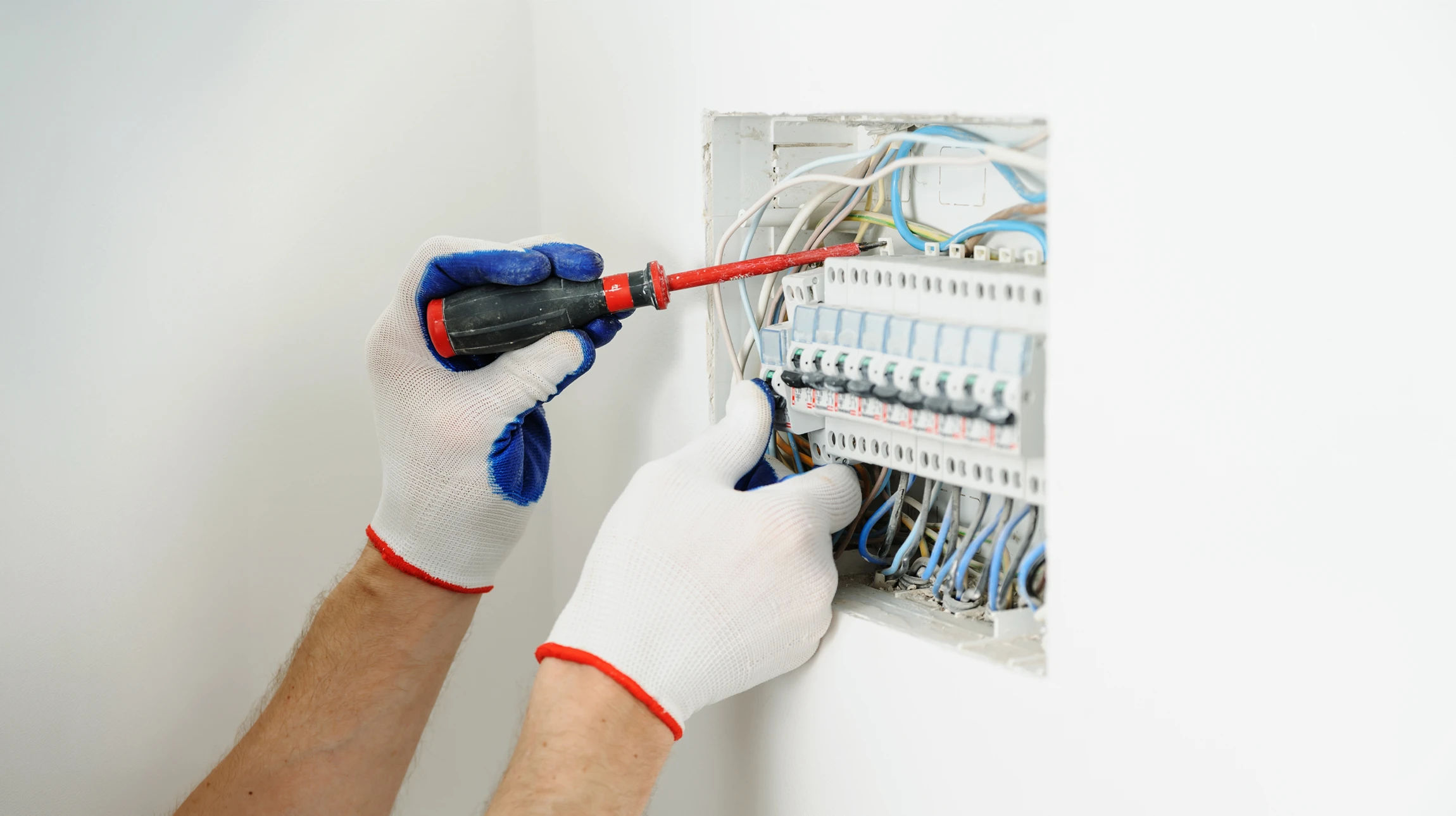 Électricien utilisant un tournevis pour pousser le câble électrique dans le Brise